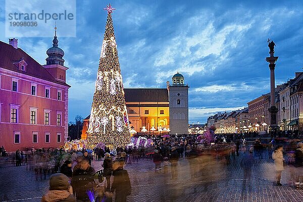 Weihnachtsbaum und Menschen auf dem Schlossplatz in der Altstadt von Warschau  Polen  in der Abenddämmerung beleuchtet  Europa