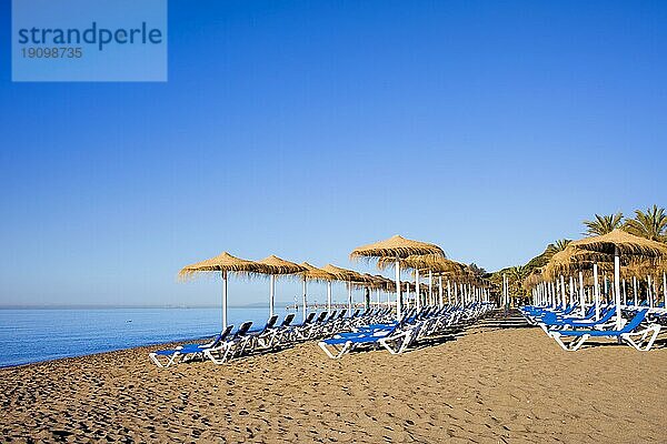 Sonnenliegen an einem ruhigen Strand in der beliebten Urlaubsstadt Marbella in Spanien  Costa del Sol  Provinz Malaga