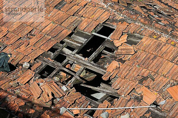 Loch im beschädigten Ton Ziegel Dach mit Holzrahmen eines traditionellen Gebäudes