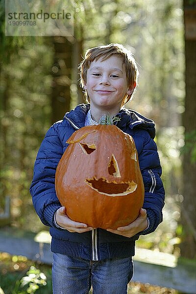 Junge hebt stolz einen Halloween Kürbis im Herbst  Kind im Herbst  Oberbayern  Bayern  Deutschland  Europa