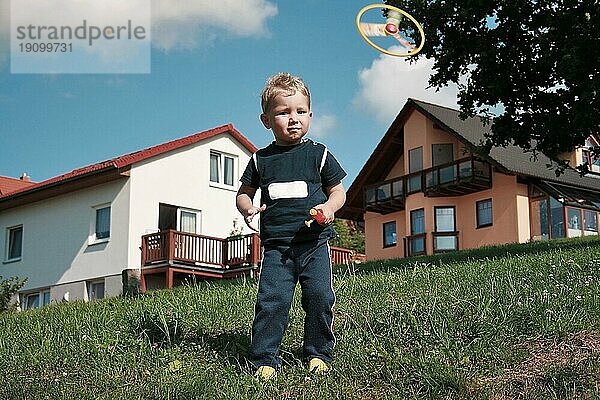 Kleiner Junge spielt mit Propeller-Spielzeug im Sommer