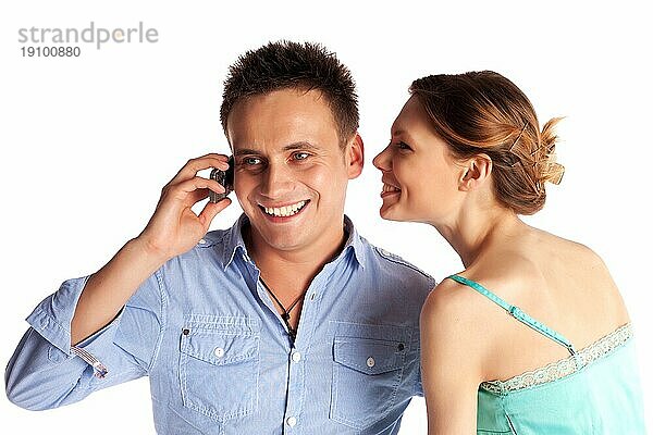 Fröhliches junges Paar beim Telefonieren vor weißem Hintergrund