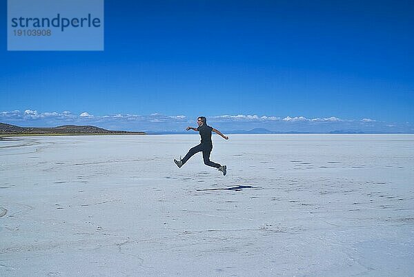 Junger Mann springt auf riesige Salzebene Salar de Uyuni in Bolivien