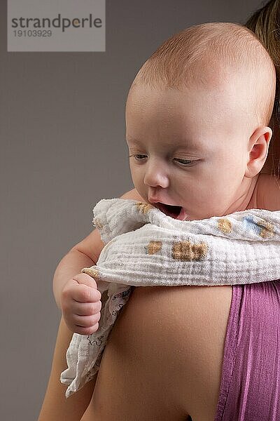 Kleines zehn Wochen altes Baby auf der Schulter der Mutter