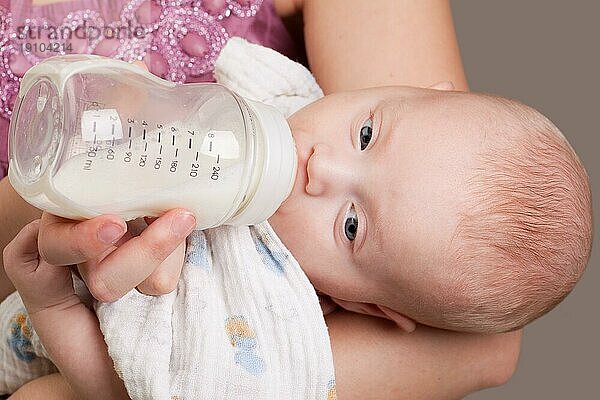 Kleines hungriges Mädchen trinkt Milch aus der Flasche