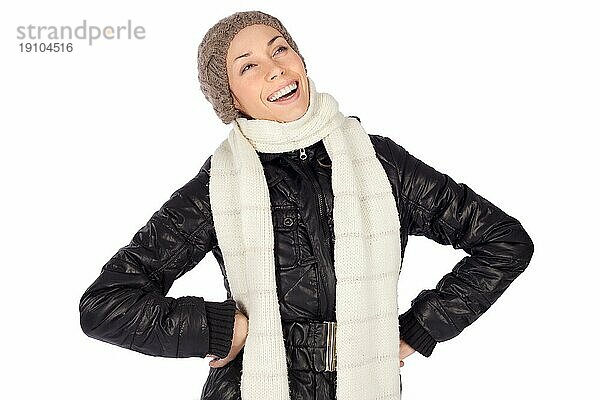 Glückliche junge Frau in lässiger Winterkleidung und Hände auf den Hüften lachend  vor weißem Hintergrund