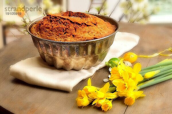 Kuchen in Form und Narzissen auf einem Tisch