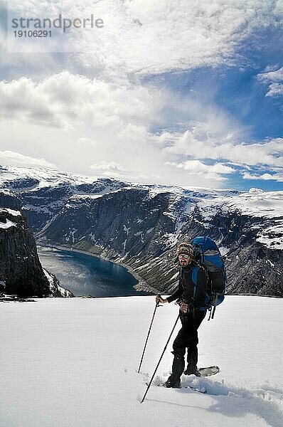 Wanderer macht eine Pause auf dem Gipfel eines schneebedeckten Berges in der Nähe von Trolltunga  Norwegen  Europa