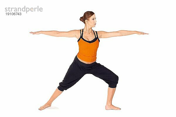 Fit attraktive junge Frau übt Yogaübung genannt Warrior Pose 2  Sanskrit Name: Virabhadrasana 2  diese Haltung stärkt und dehnt Beine  Knöchel  Leisten  Brust  Lunge und Schultern