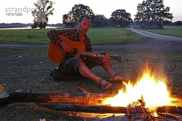 Mann an einem Lagerfeuer spielt Gitarre  Sachsen-Anhalt  Deutschland  Europa