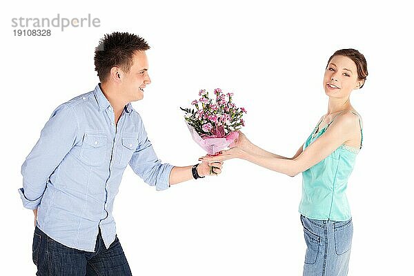 Fröhliches lässiges Paar vor weißem Hintergrund  romantischer Mann gibt seiner Freundin Blumen