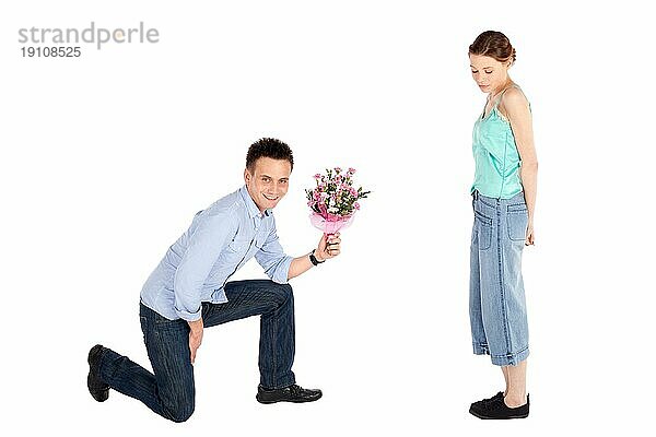 Glücklicher gutaussehender junger Mann  der einer schönen jungen Frau eine Blume überreicht  vor weißem Hintergrund