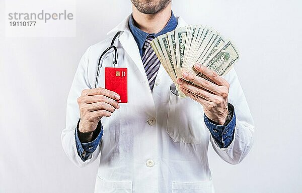Unerkennbarer Arzt hält Geld und Kreditkarten isoliert. Arzt Hände halten Kreditkarte und Geld isoliert