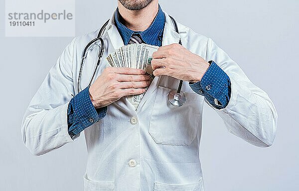 Unehrlicher Arzt steckt Geld in die Tasche. Medizinische Bestechung Konzept  korrupte Arzt setzen Bestechungsgeld in der Tasche isoliert
