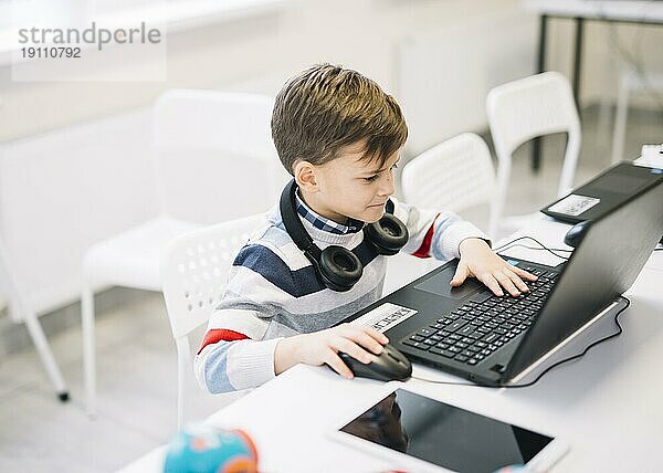Kleiner Junge benutzt Laptopschreibtisch im Klassenzimmer