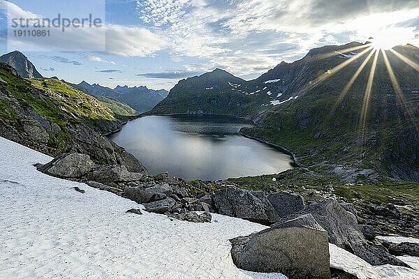 Berglandschaft mit See Tennesvatnet  bei Sonnenaufgang mit Sonnenstern  Moskenesøya  Lofoten  Nordland  Norwegen  Europa