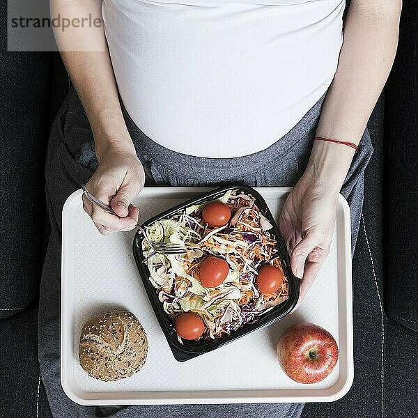 Draufsicht schwangere Frau mit Salat
