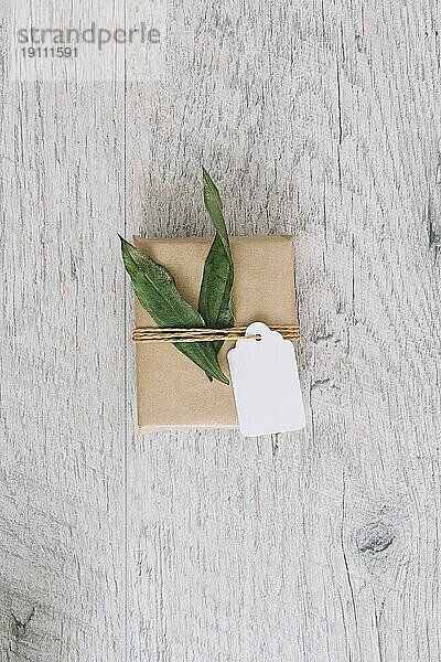 Draufsicht braun verpackt Geschenkbox mit Tag grüne Blätter Holztisch