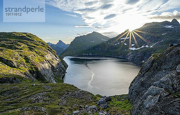 Berglandschaft mit See Tennesvatnet  bei Sonnenaufgang mit Sonnenstern  Moskenesøya  Lofoten  Nordland  Norwegen  Europa