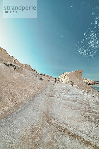 Schöne weiße Felsen von Sarakiniko Strand  Ägäisches Meer  Insel Milos  Griechenland. Einsame unerkennbar Erwachsenen  leere Klippen  Sommertag Sonne  Mondlandschaft  fantastische Felsen von Touristenziel  Himmel  Wolken  cyan rosa Farben  vertikale Schuss