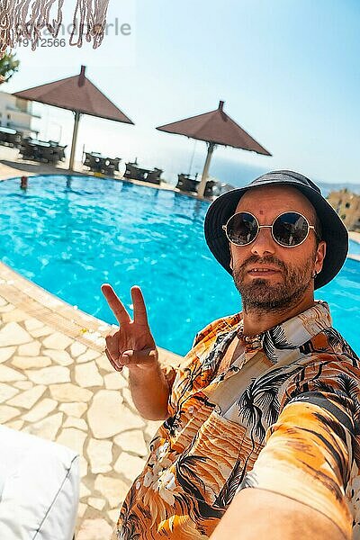 Tourist Mann im Hotelpool im Sommer ein Selfie genießen den Urlaub  so dass der Sieg Symbol