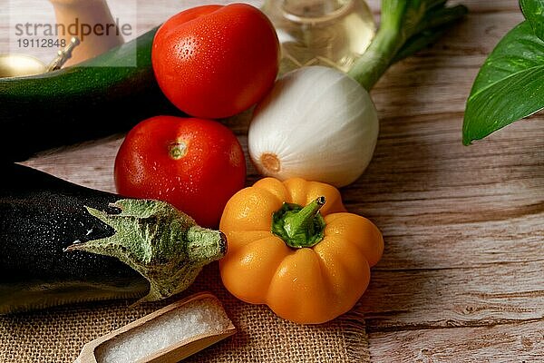 Draufsicht auf eine Gruppe frischer Gemüsesorten zur Zubereitung eines vegetarischen Menüs  Paprika  Zwiebel  Tomate  Aubergine  Zucchini  Olivenöl  Eierpflanze
