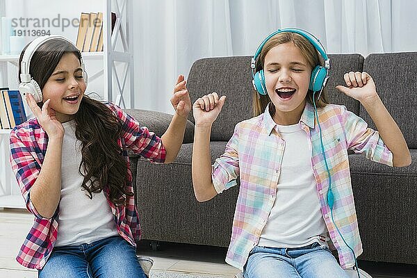 Zwei Freundinnen genießen Musik Kopfhörer zu Hause