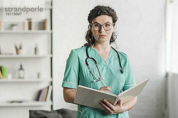 Porträt weibliche Krankenschwester hält Buch Stift