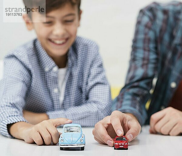 Lächelnder kleiner Junge spielt mit Spielzeugautos