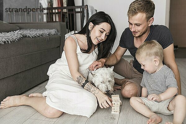 Glückliche Familie spielt Blöcke Holz Turm Spiel mit Hund