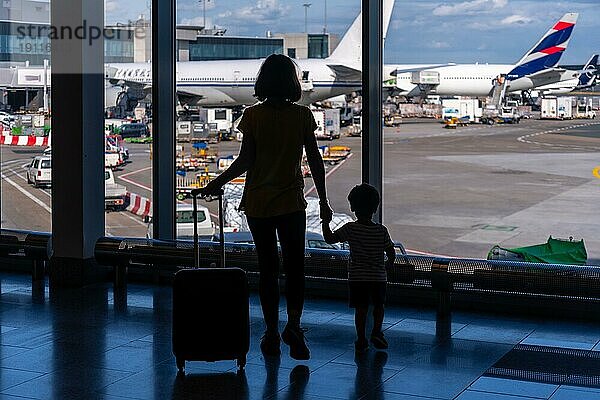 Silhouette von Mutter und Sohn mit Gepäck stehen in der Nähe des Fensters in den Flughafen  Urlaub Konzept