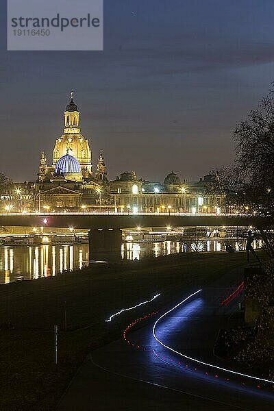 Die Frauenkirche mit der Glaskuppel über dem Oktogon der Kunstakademie  diese ist aus Protest gegen den Ukraine Krieg  blau beleuchtet. Im Vordergrund Lichtstreifen von Radfahrern in der Dunkelheit auf dem Elberadweg