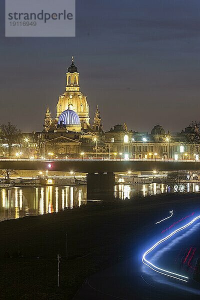 Die Frauenkirche mit der Glaskuppel über dem Oktogon der Kunstakademie  diese ist aus Protest gegen den Ukraine Krieg  blau beleuchtet. Im Vordergrund Lichtstreifen von Radfahrern in der Dunkelheit auf dem Elberadweg