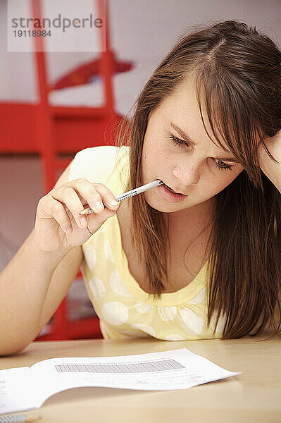 Junges Mädchen lernt mit Bleistift im Mund