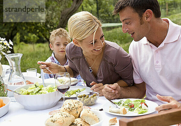 Paar und kleiner Junge essen draußen zu Mittag