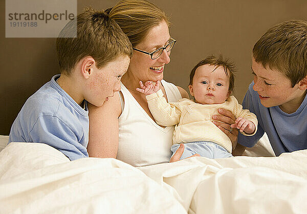 Porträt einer Frau im Bett mit ihren Kindern und ihrem Neugeborenen