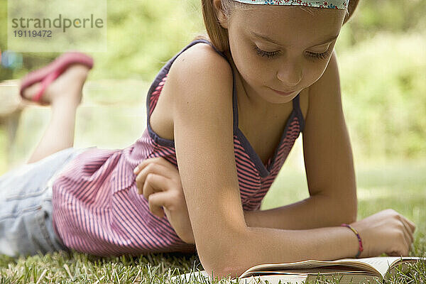 Mädchen liegt auf dem Bauch und liest ein Buch
