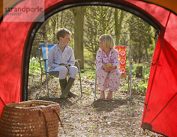 Porträt eines Jungen und eines Mädchens  die vor dem Zelteingang sitzen