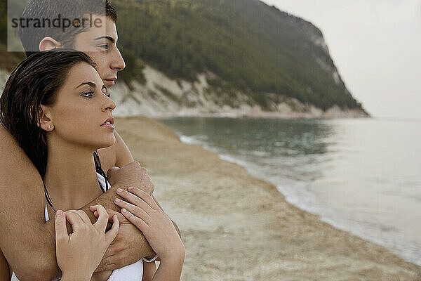 Junges Paar umarmt sich am Strand