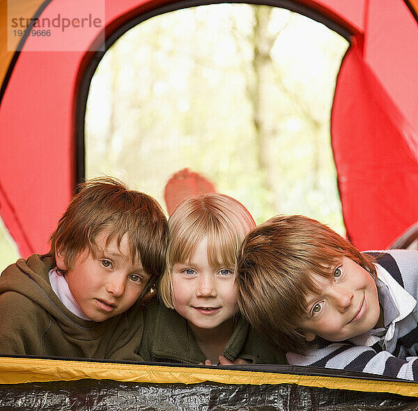 Porträt von drei Kindern  die in einem Zelt liegen