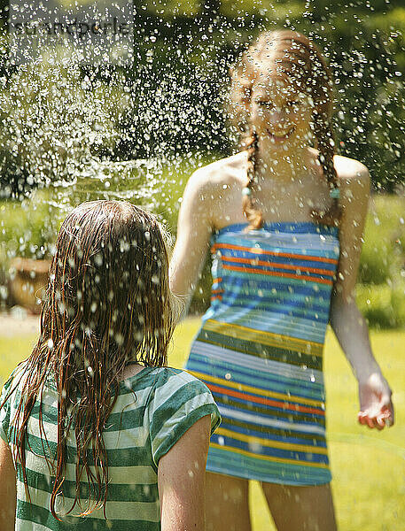 Porträt eines Teenagers  der ein Mädchen mit Wasser besprüht