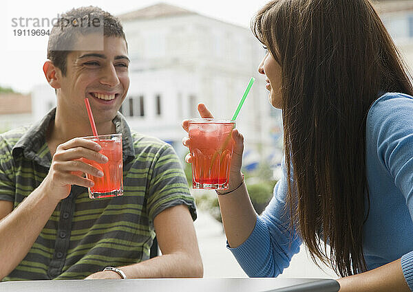 Porträt eines jungen Paares  das sitzt und Cocktails trinkt