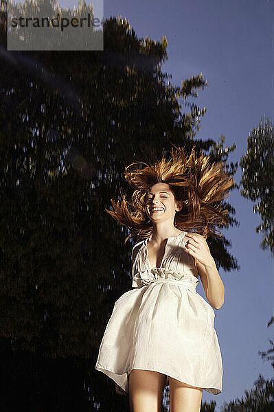 Lachende junge Frau springt vom Trampolin in die Luft
