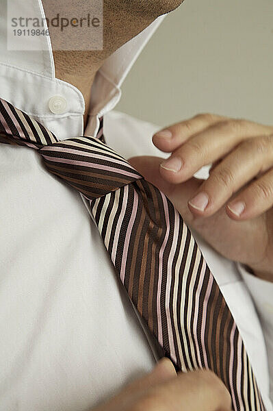 Extreme Nahaufnahme der Hände eines Mannes  der eine Krawatte bindet