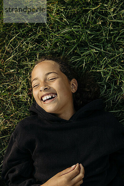 Unmittelbar über der Aufnahme eines sorglosen Mädchens  das lachend im Sommerlager im Gras liegt