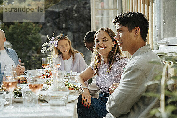 Porträt einer lächelnden jungen Frau  die mit Freunden bei einer Dinnerparty im Café sitzt