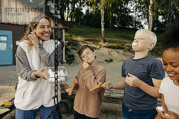 Kinder essen Snacks mit einem Betreuer  der einen Behälter im Ferienlager hält