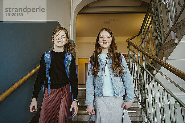 Porträt von glücklichen Freundinnen auf der Treppe eines Schulgebäudes