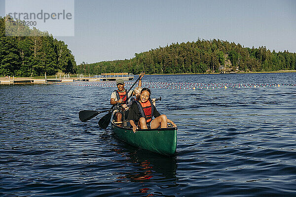 Lächelndes Mädchen beim Kajakfahren mit Betreuer auf einem See im Sommercamp