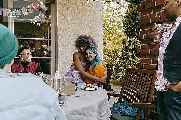 LGBTQ-Freunde umarmen sich während einer Dinnerparty im Hinterhof